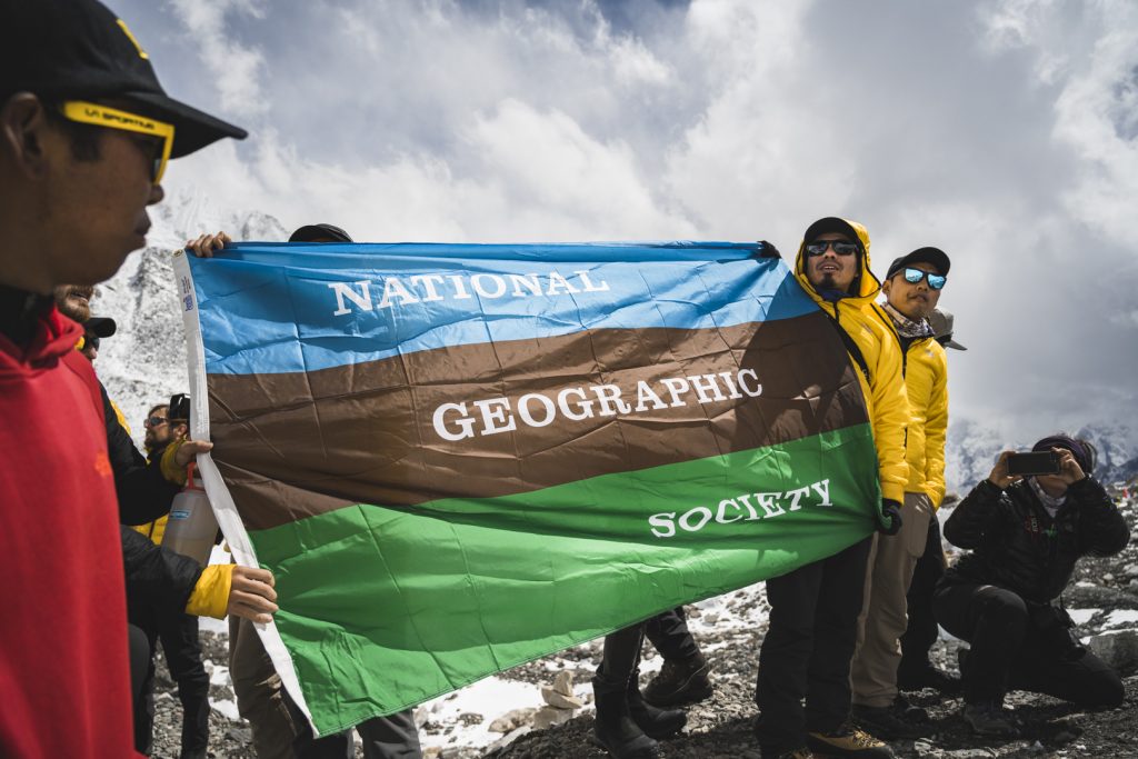Part of the National Geographic and Rolex Perpetual Planet Expedition team holding up a National Geographic Society flag.